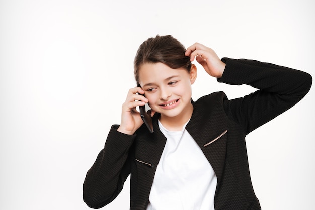 Confused young girl standing and talking by phone