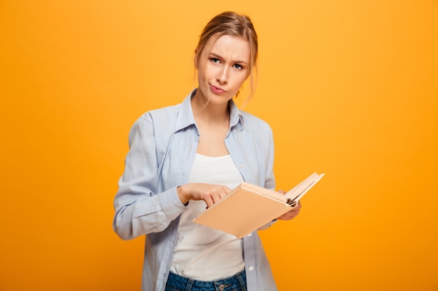 Confused young lady student reading book.