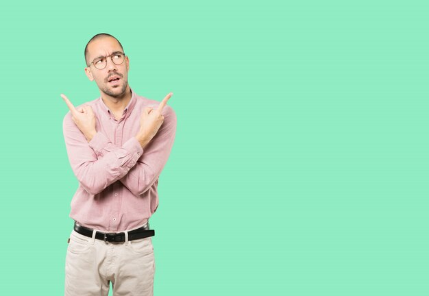 Confused young man poiting in both directions