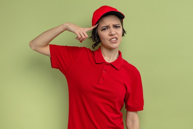 Confused young pretty delivery woman putting finger on her forehead and looking 