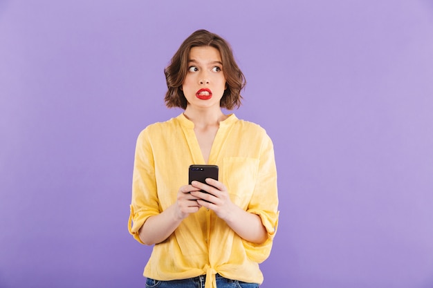 Confused young woman isolated over purple wall