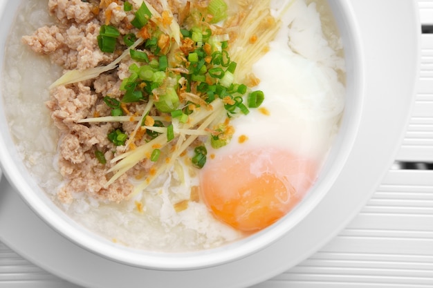 congee with soft boiled egg and vegetable in bowl