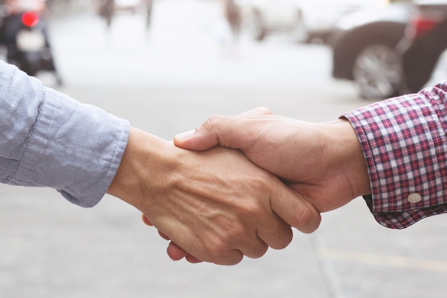 Congratulazioni. primo piano di un giovane uomo d'affari che stringe la mano al concessionario dell'auto nel salone dell'auto dopo un accordo di successo