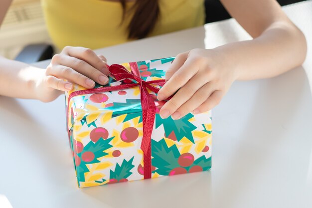 Congratulations on the holiday. The girl opens the box with a gift, untie the ribbon, removes the wrapping paper