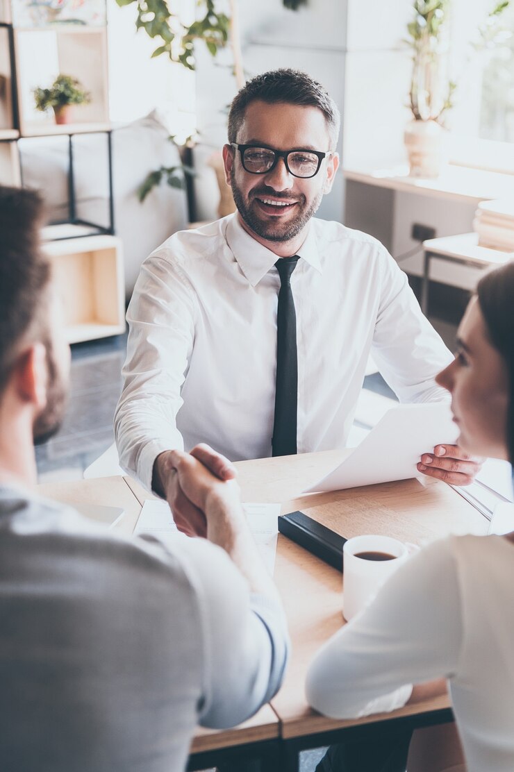 Photo congratulations! two men sitting at the desk and shaking hands while young woman looking at them
