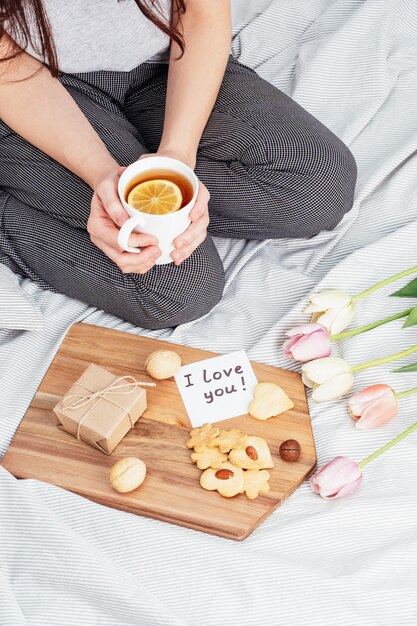 Congratulations to your favorite girl on Valentine's Day. Breakfast in bed. A woman in pajamas accepts gifts on February 14.