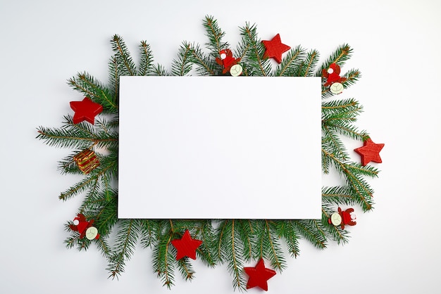 Congratulatory Christmas background with an empty white sheet and green branches of spruce 