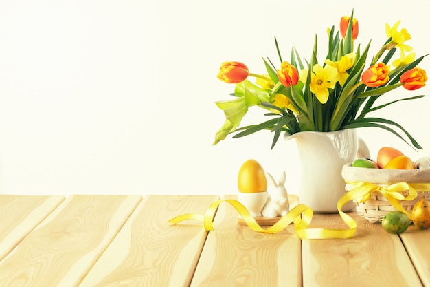 Congratulatory easter background. Easter eggs and flowers on wooden background. Happy Easter card.