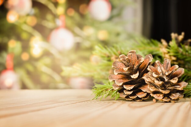 Coniferenkegels en vuren takken op een houten tafel tegen de achtergrond van een kerstboom