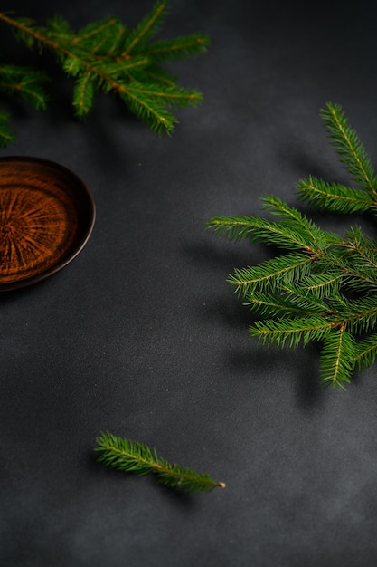 Coniferous branches on dark background top view Empty Clay Old Plate in corner Christmas concept
