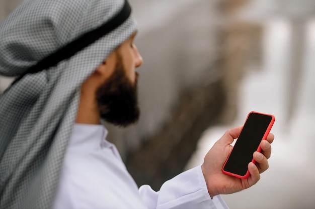 Collegato. uomo arabo con uno smartphone in mano