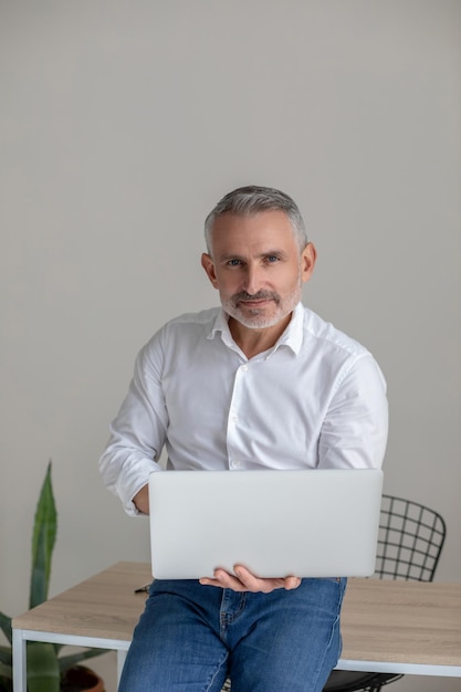 Connected. Good-looking gray-haired man working on laptop