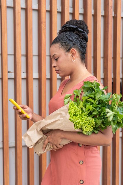 Photo connected shopper with fresh greens and smartphone