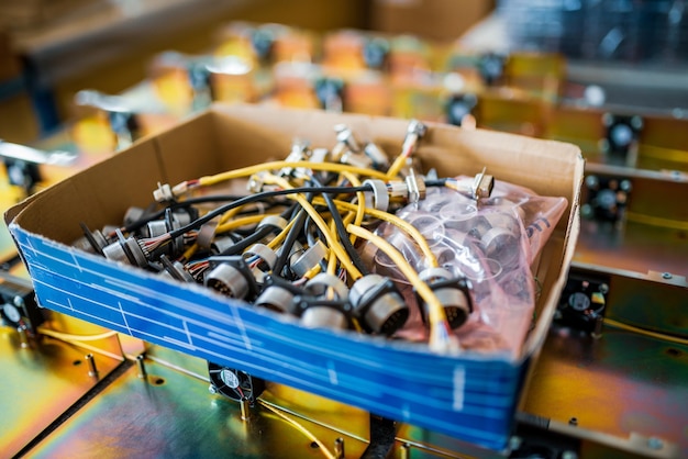 Connecting cords with metal plugs for contemporary TFT monitors in cardboard box in production plant workshop extreme close view