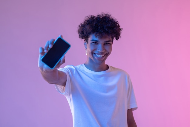 Connection. Headshot of curly-haired smiling guy with a smartphone