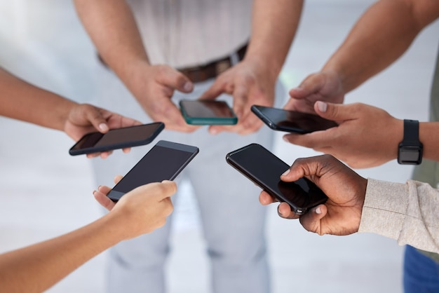 A connection that leads to success Closeup shot of a group of businesspeople using their cellphones in synchronicity in an office