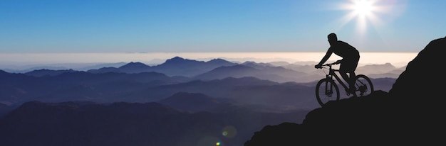 Conquering mountain peaks by cyclist in shorts and jersey on a modern carbon hardtail bike with an air suspension fork Beautiful view from the mountain Panoramic view for banner