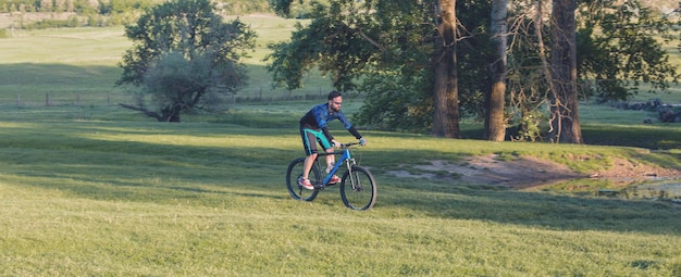 에어 서스펜션 포크가 있는 현대적인 탄소 하드테일 자전거를 타고 반바지와 저지를 입은 사이클리스트의 산봉우리 정복