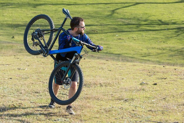 Foto conquista delle vette da ciclista in pantaloncini e maglia su una moderna bici hardtail in carbonio con forcella a sospensione pneumatica