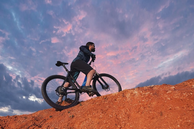 Conquering mountain peaks by cyclist in shorts and jersey on a modern carbon hardtail bike