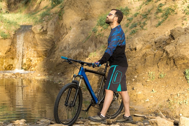 モダンなカーボンハードテイルバイクでショートパンツとジャージを着たサイクリストが山頂を征服