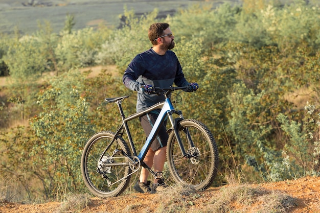 Conquering mountain peaks by cyclist in shorts and jersey on a modern carbon hardtail bike