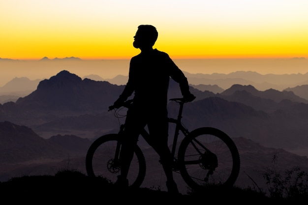 현대적인 카본 하드테일 자전거를 타고 반바지와 저지를 입은 사이클리스트의 산봉우리 정복