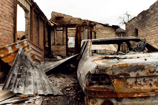 The consequences of Russia's military aggression against burnt house with a car in bucha and irpen war between russia and ukraine shelling with rockets broken houses disaster in ukraine