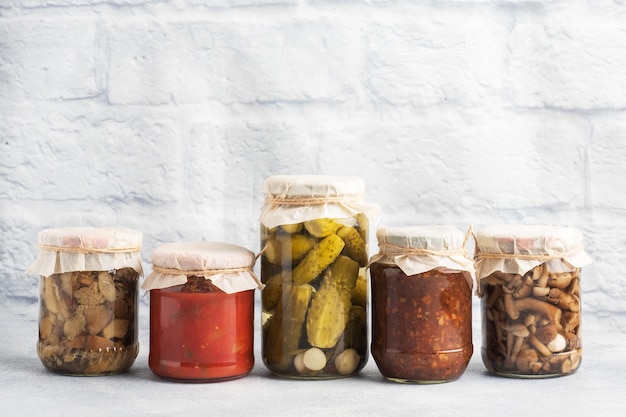 Conservering van groenten in banken. Fermentatieproducten. Tomaten en bessen oogsten, champignons voor de winter. Kopieer ruimte.