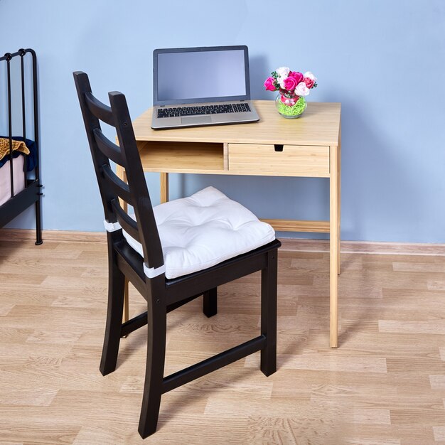 Console table with storage and laptop on it and chair with\
pillow