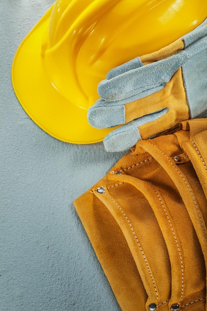 Construction belt safety gloves hard hat on concrete background.