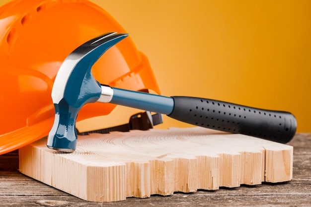 Construction blue hammer with an orange helmet on a yellow background Concept of construction and repair