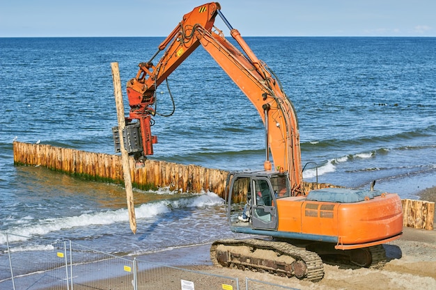 Строительство волноломов из стволов деревьев на берегу моря.