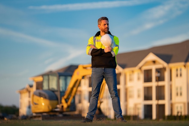 Construction build man with excavator at industrial site worker in helmet with bulldozer engineer