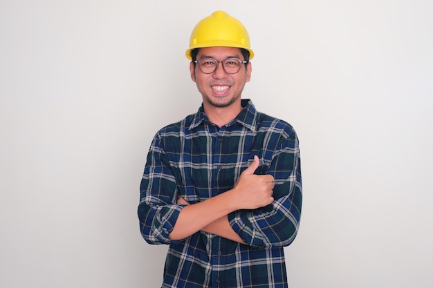 Photo a construction builder wearing hardhat smiling and give thumb up with arms crossed