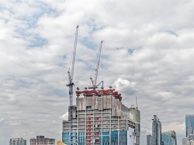 Edificio in costruzione con gru e lavoratori contro il cielo nuvoloso