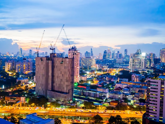 Construction of building with three tower cranes at twilight