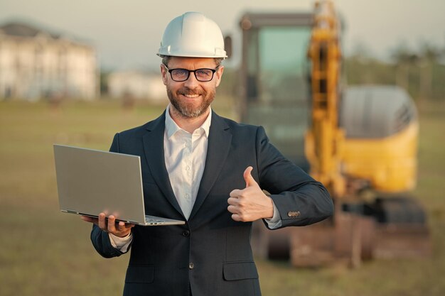 Construction business owner Man in suit and hardhat halmet at building construction site Civil engineer worker in front of house near excavator Architect supervisor investor construction manager