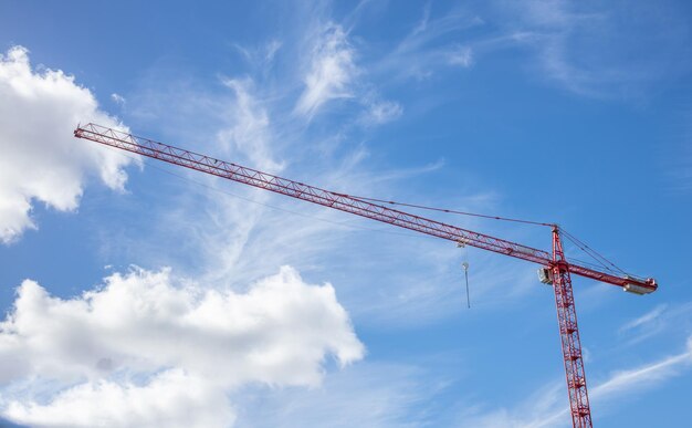 Construction concept Red tower crane under cloudy sky background Under view space