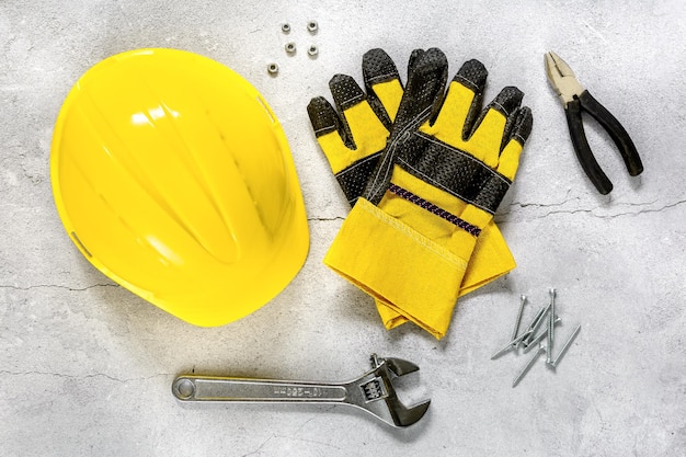 Construction concept yellow protective helmet and gloves on a
gray concrete background