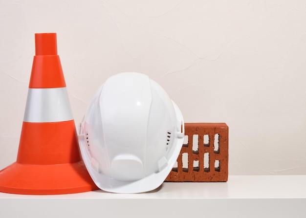 Construction cone white head protection helmet and facing brick Copy space for text