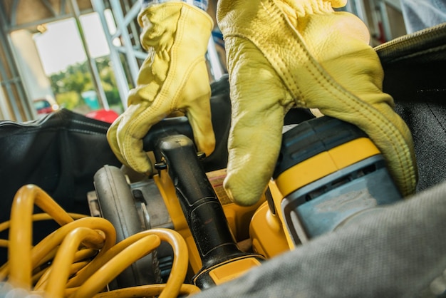 Photo construction contractor grabbing power tools from his equipment bag close up