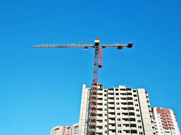 Construction crane at blue sky and unfinished building house