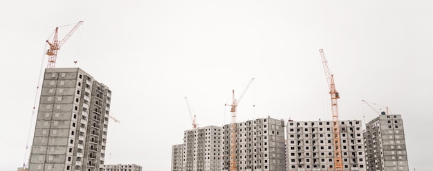 The construction crane and the building against the blue sky