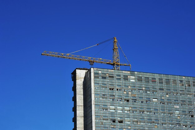 Construction crane and an old building made of concrete blocks