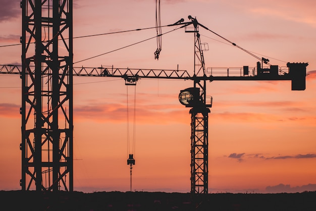 Photo construction crane silhouettes at sunset.