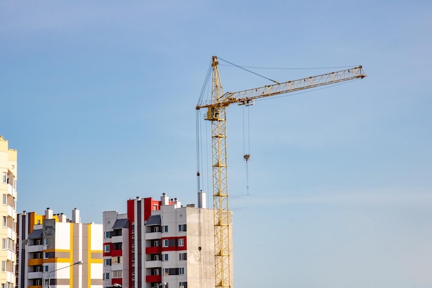 Construction crane and tall houses on blue sky background