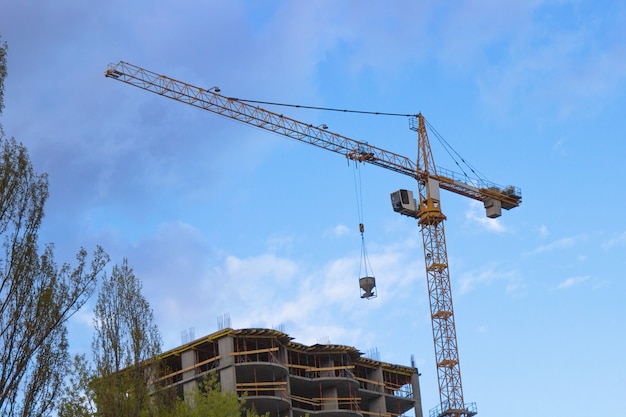 Construction cranes and buildings over sky