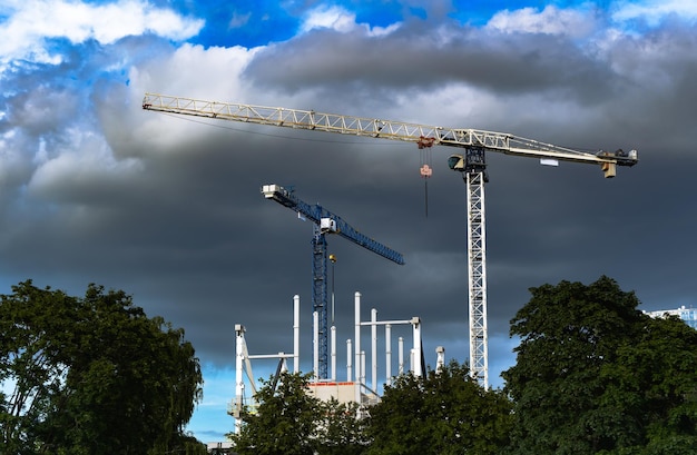 Construction cranes on the cloudy sky