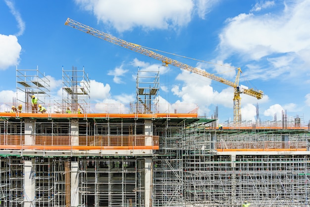 Construction cranes and high-rise building under construction against blue sky.